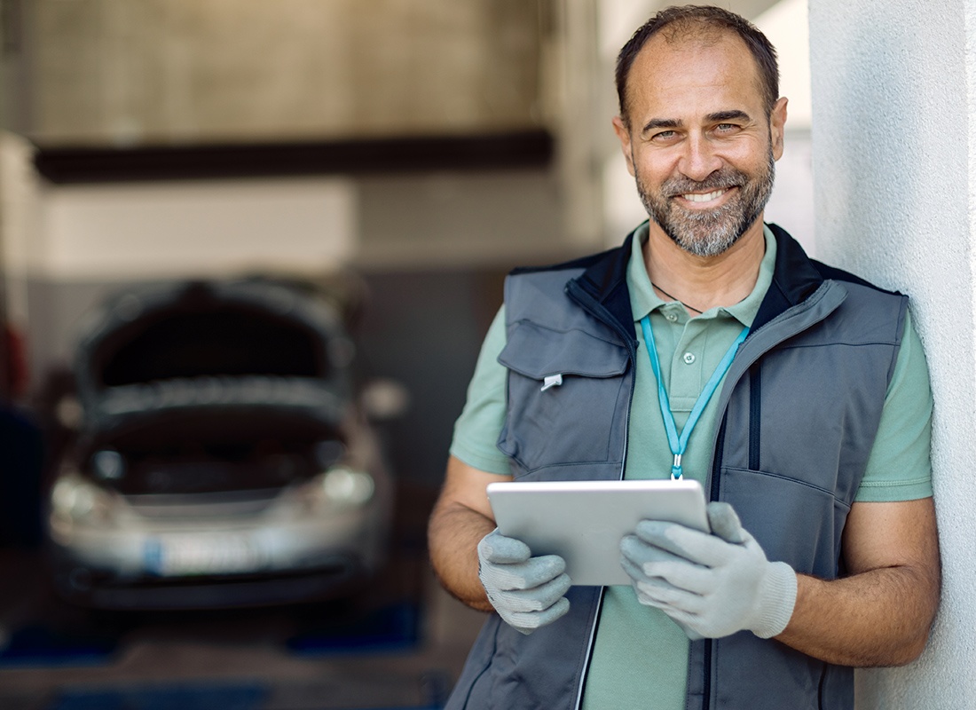 Service Center - Happy Auto Mechanic Using Digital Tablet in a Workshop